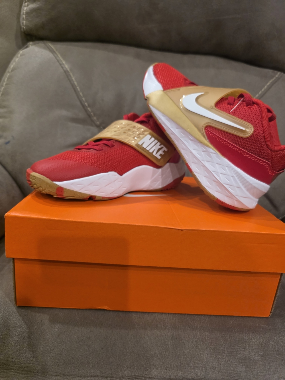 Nike Team Hustle D 12 basketball shoes in a vibrant red and gold colorway.